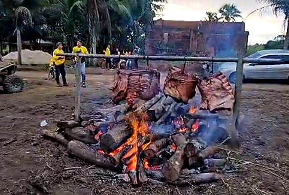 Costelas douradas no fogo de chão ao fim de tarde, com sítio histórico ao fundo