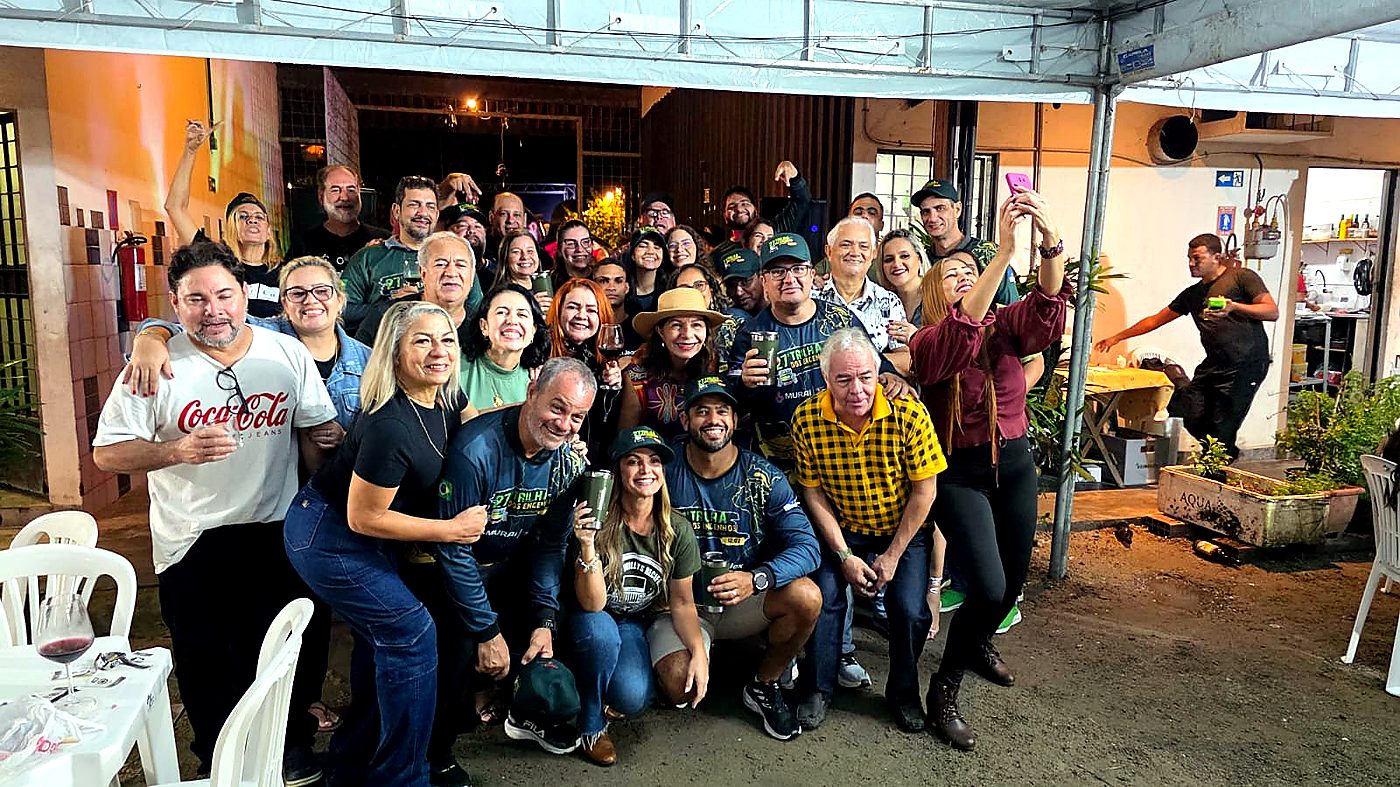 Galera reunida na recepção, taças nas mãos, camisas oficiais
